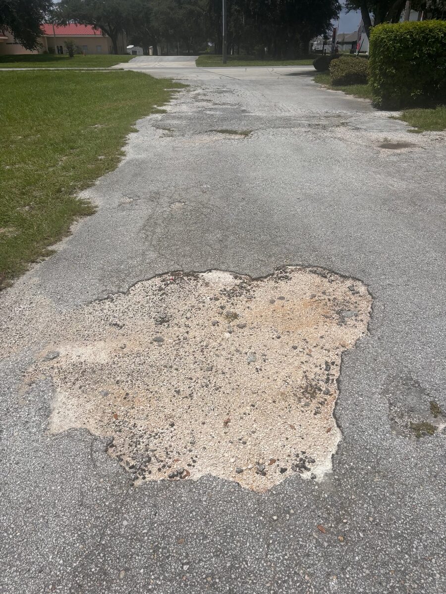 Large pothole in driveway approach to commercial parking lot