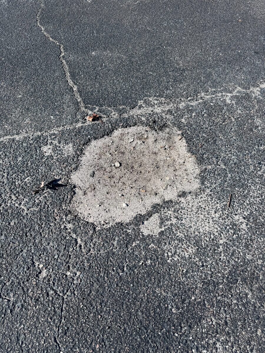 Sunken and washed-out old patch in a cracked parking lot
